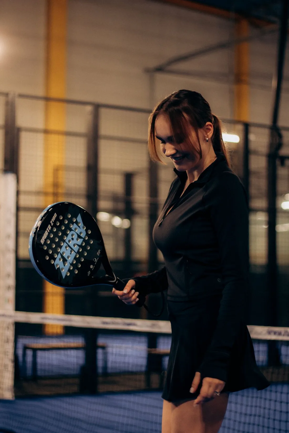 Joueuse tenant sa raquette de padel dans un club couvert