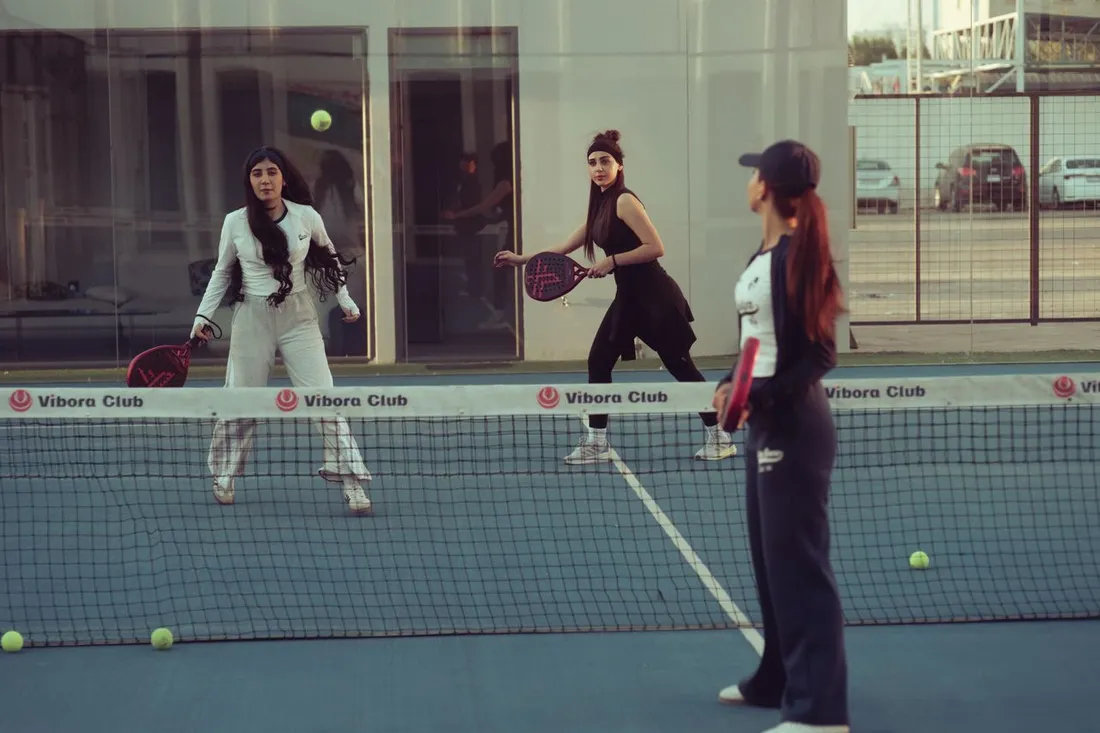 Trois joueuses lors d'une partie de padel en double sur un terrain de club